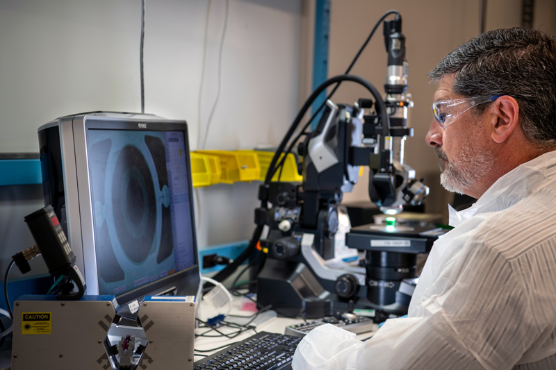 Viant engineer studying medical device prototyping component under microscope